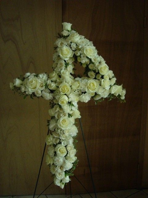 A cross made of white roses on a stand