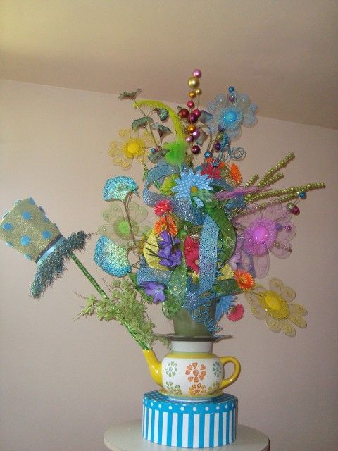 A teapot with flowers and a hat on top of it