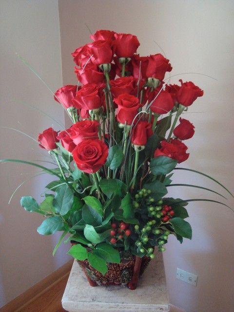 A vase filled with red roses and greenery