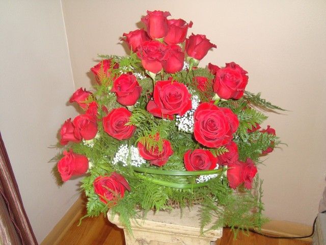A vase filled with red roses and greenery
