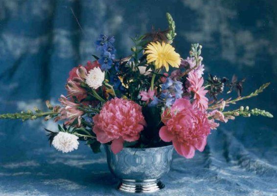 A silver vase filled with pink and yellow flowers