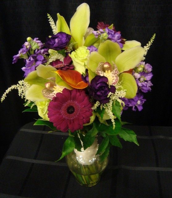 A vase filled with purple yellow and green flowers