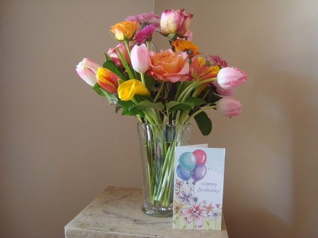 A vase of flowers next to a birthday card