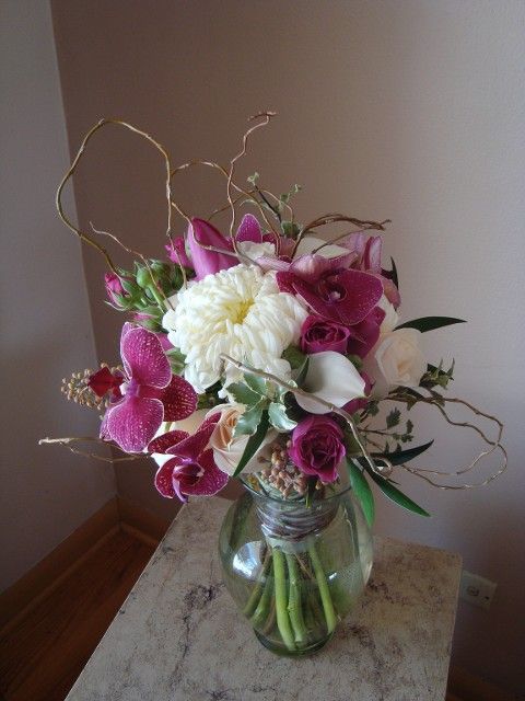 A vase filled with purple and white flowers is sitting on a table.