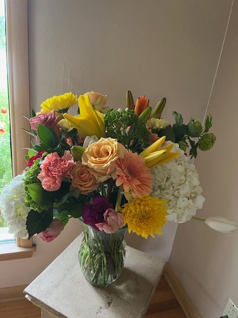 A vase filled with flowers is sitting on a table in front of a window.