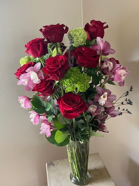 A vase filled with red roses and pink flowers