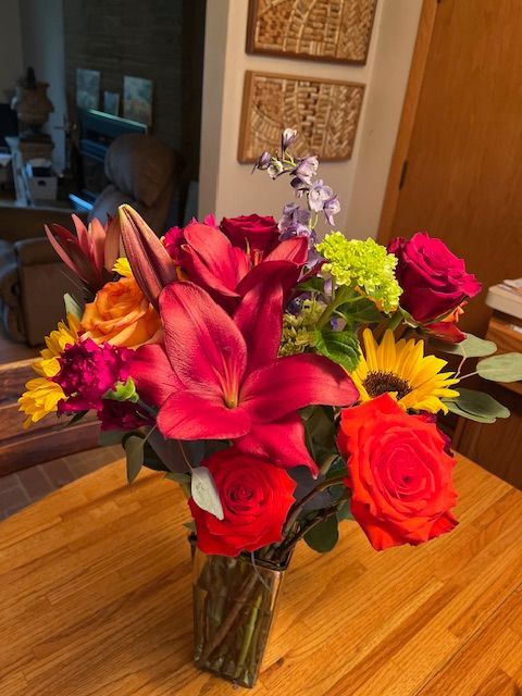 A vase filled with flowers is sitting on a wooden table.