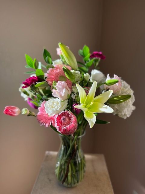 A vase filled with pink and white flowers is sitting on a table.