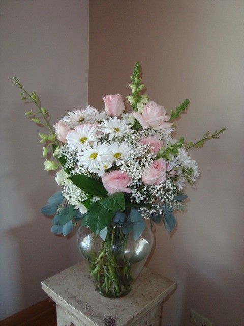 A vase filled with pink roses and white daisies