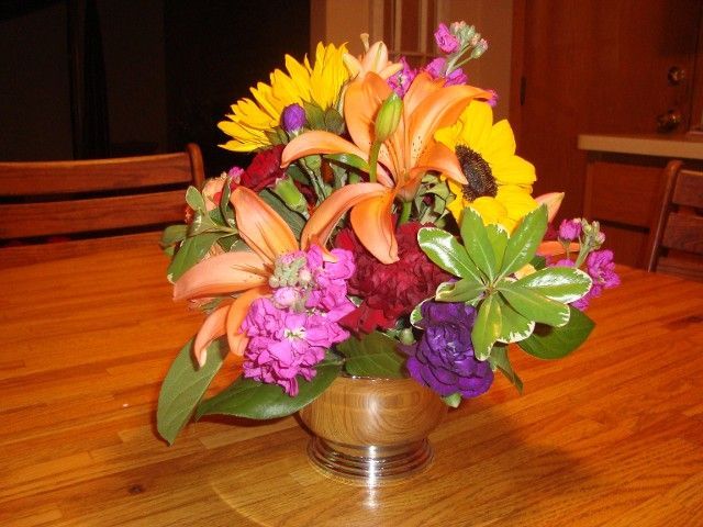 A vase filled with flowers sits on a wooden table