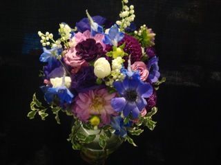 A vase filled with purple and blue flowers on a black background.