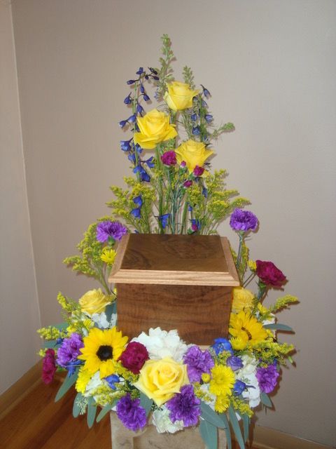 A wooden box surrounded by yellow and purple flowers