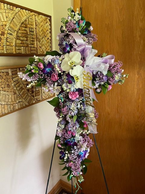 A cross with purple and white flowers on a stand