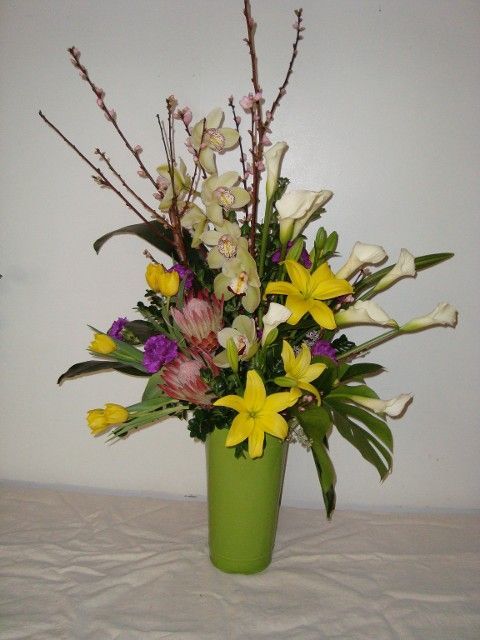 A green vase filled with flowers on a table