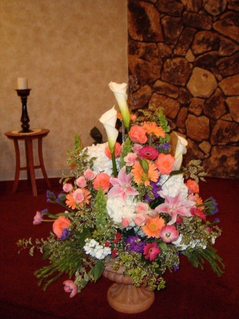 A vase filled with flowers sits in front of a stone wall