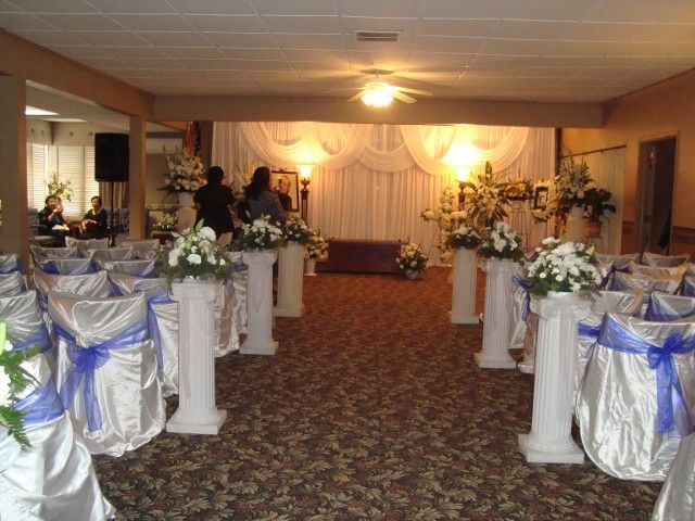 A room decorated for a wedding with white chairs and blue ribbons