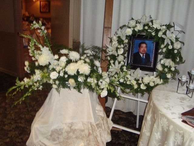 A picture of a man is surrounded by a wreath of white flowers