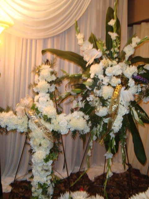 A bunch of white flowers on stands in front of a white curtain