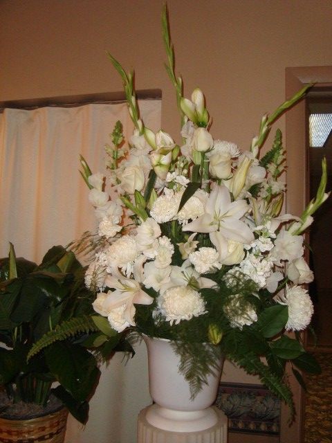 A vase filled with white flowers sits on a pedestal