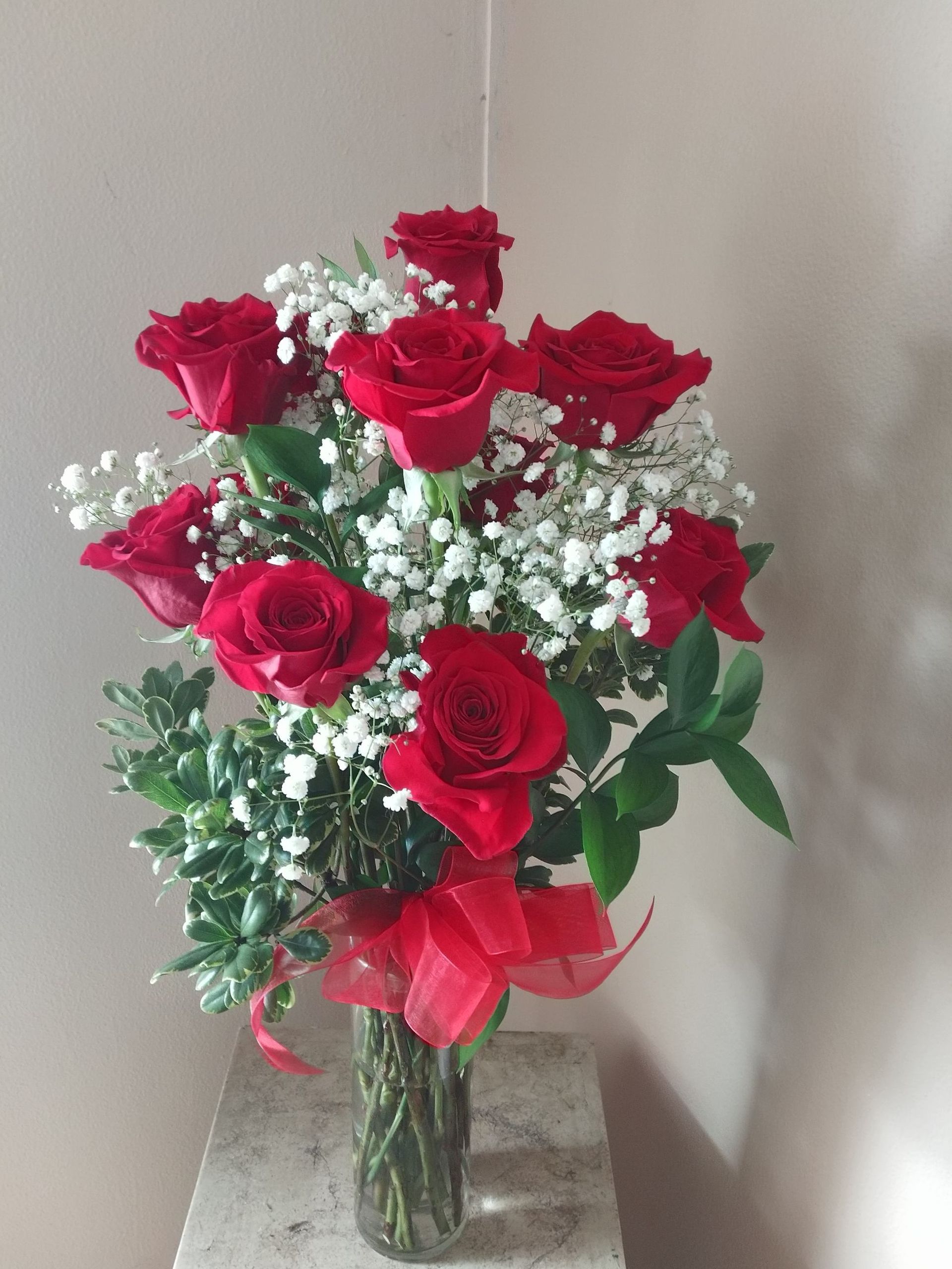 A vase filled with red roses and baby 's breath