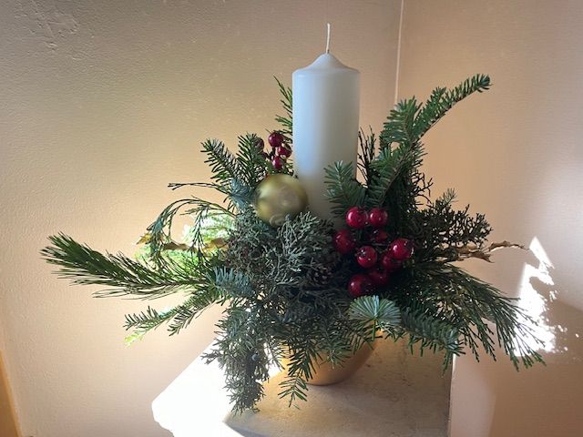 A white candle is surrounded by christmas decorations on a table.