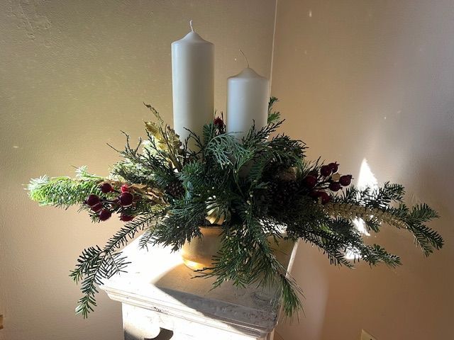 A vase filled with flowers and candles on a mantle.