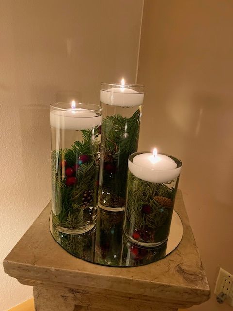 Three candles are sitting on a mirror on a table.