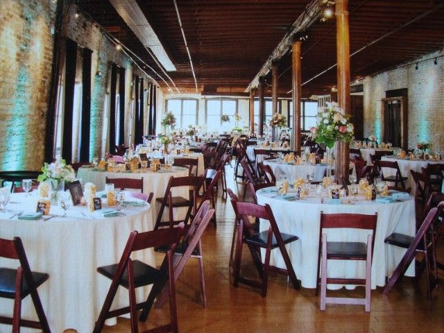 A large room with tables and chairs set up for a wedding reception