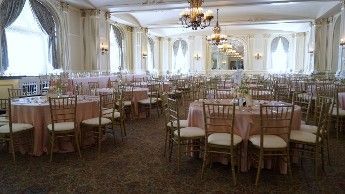 A large room filled with tables and chairs set up for a wedding reception.