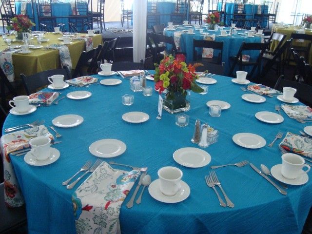 A round table with a blue table cloth and white plates