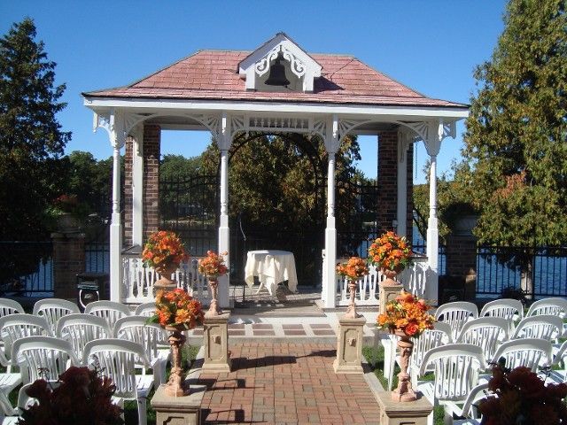 A gazebo is decorated with flowers and chairs for a wedding ceremony