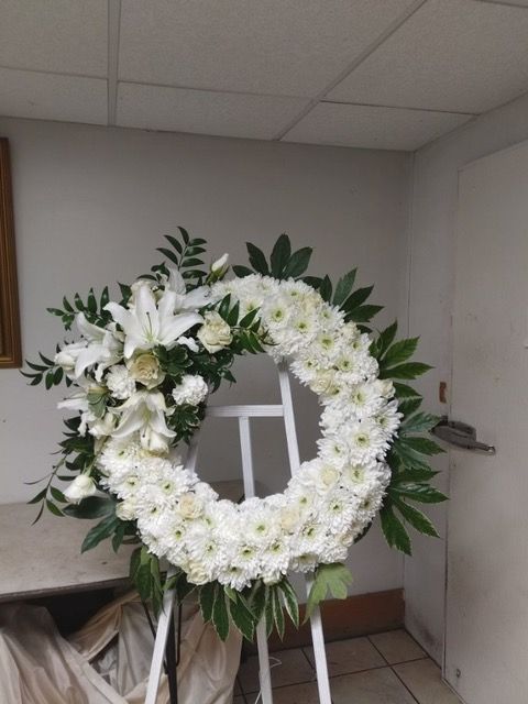 A wreath of white flowers is sitting on a white easel