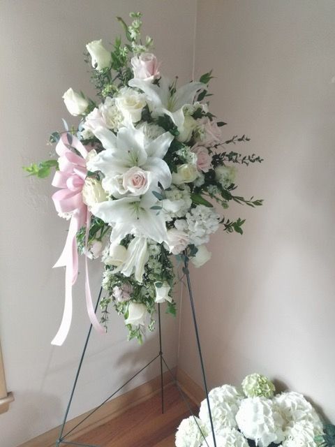 A display of white flowers with a pink bow on a stand in a room.