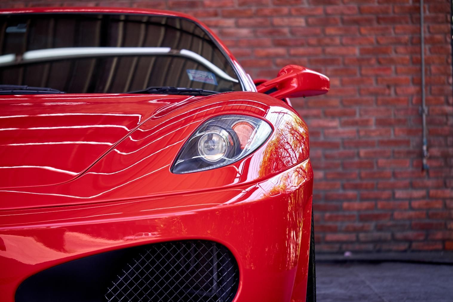 A Red Sports Car is Parked in Front of a Brick Wall — Detail World Car Detailing in Coffs Harbour, NSW