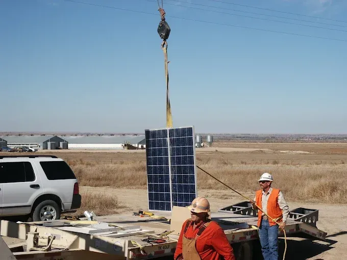 Two men are working on a solar panel on a trailer