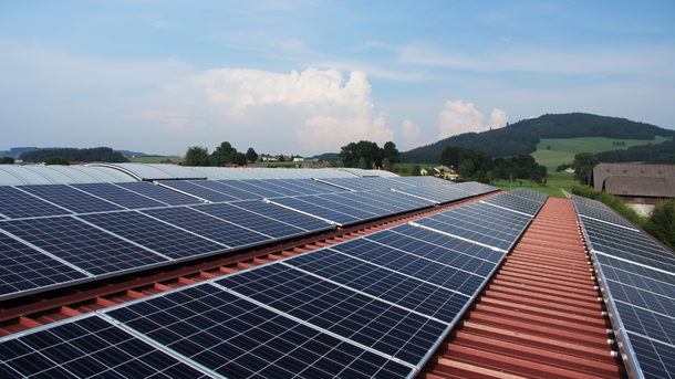 There are many solar panels on the roof of a building.