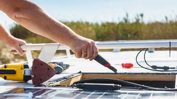 A person is working on a solar panel with a sander.