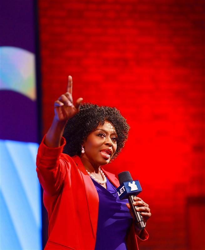 A woman in a blue jacket is speaking into a microphone