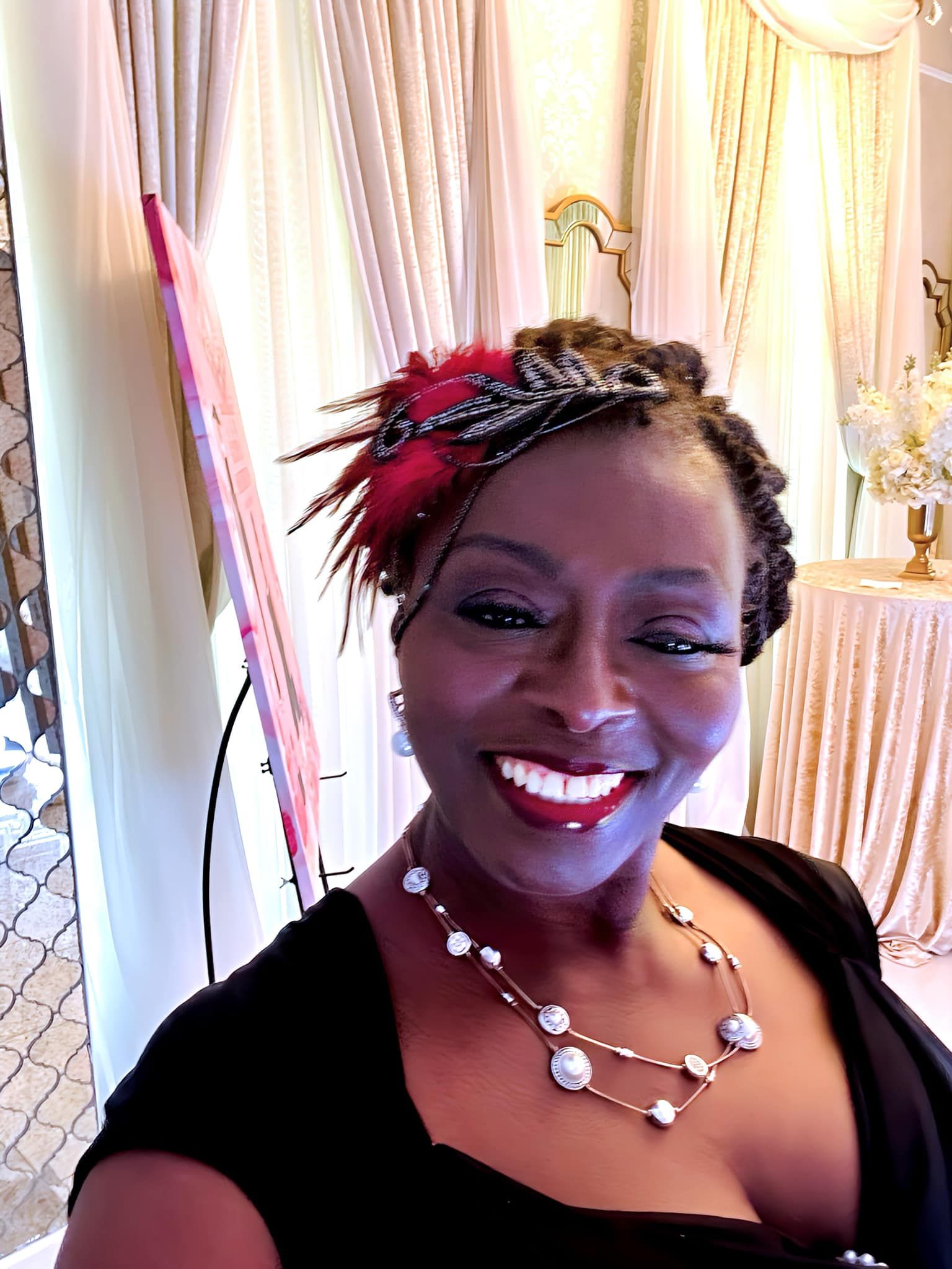 A woman wearing a black top and a necklace is smiling for the camera.