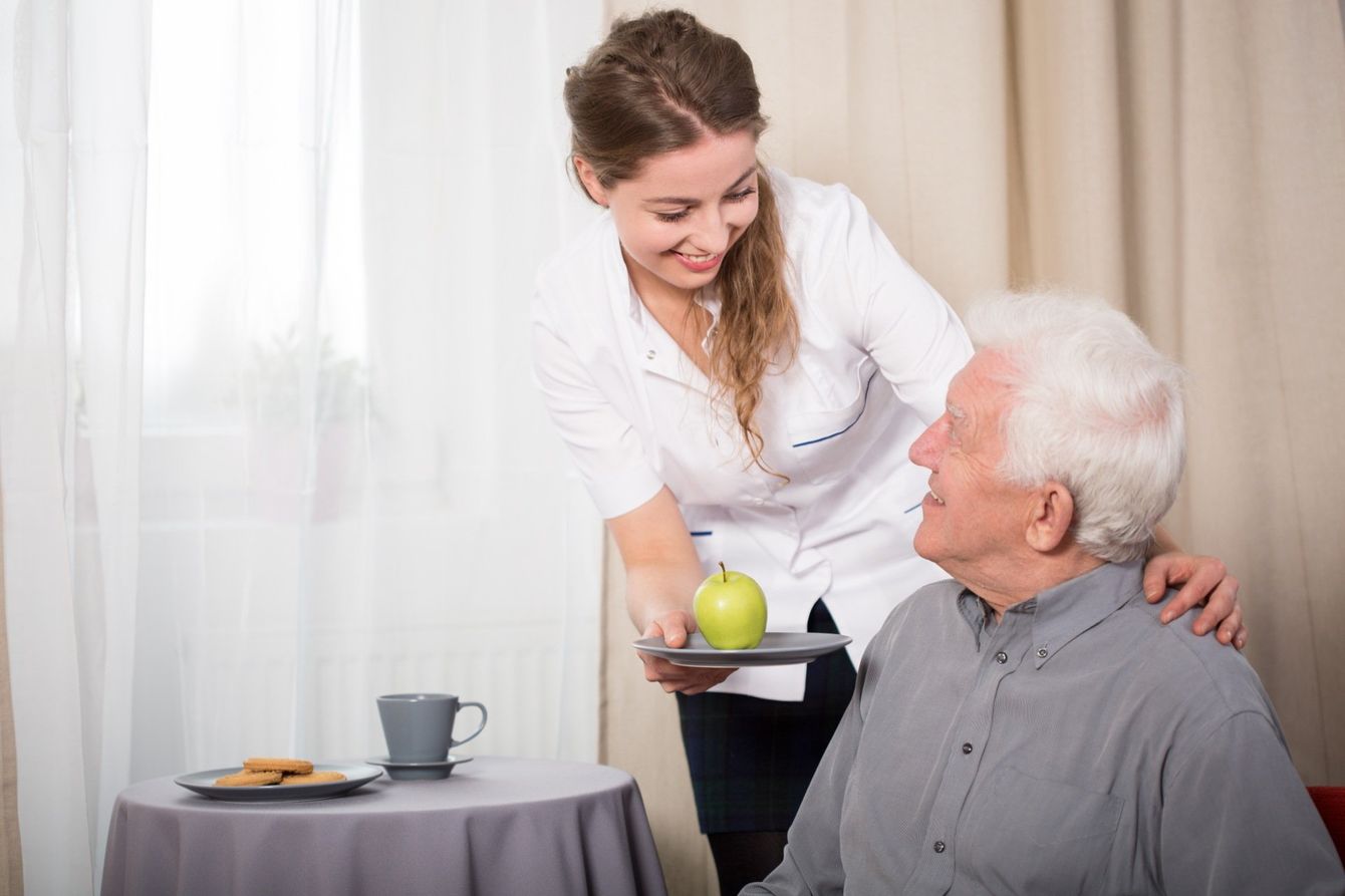 Woman serving apple to elderly man