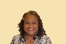 A woman with dreadlocks and a necklace is smiling for the camera.