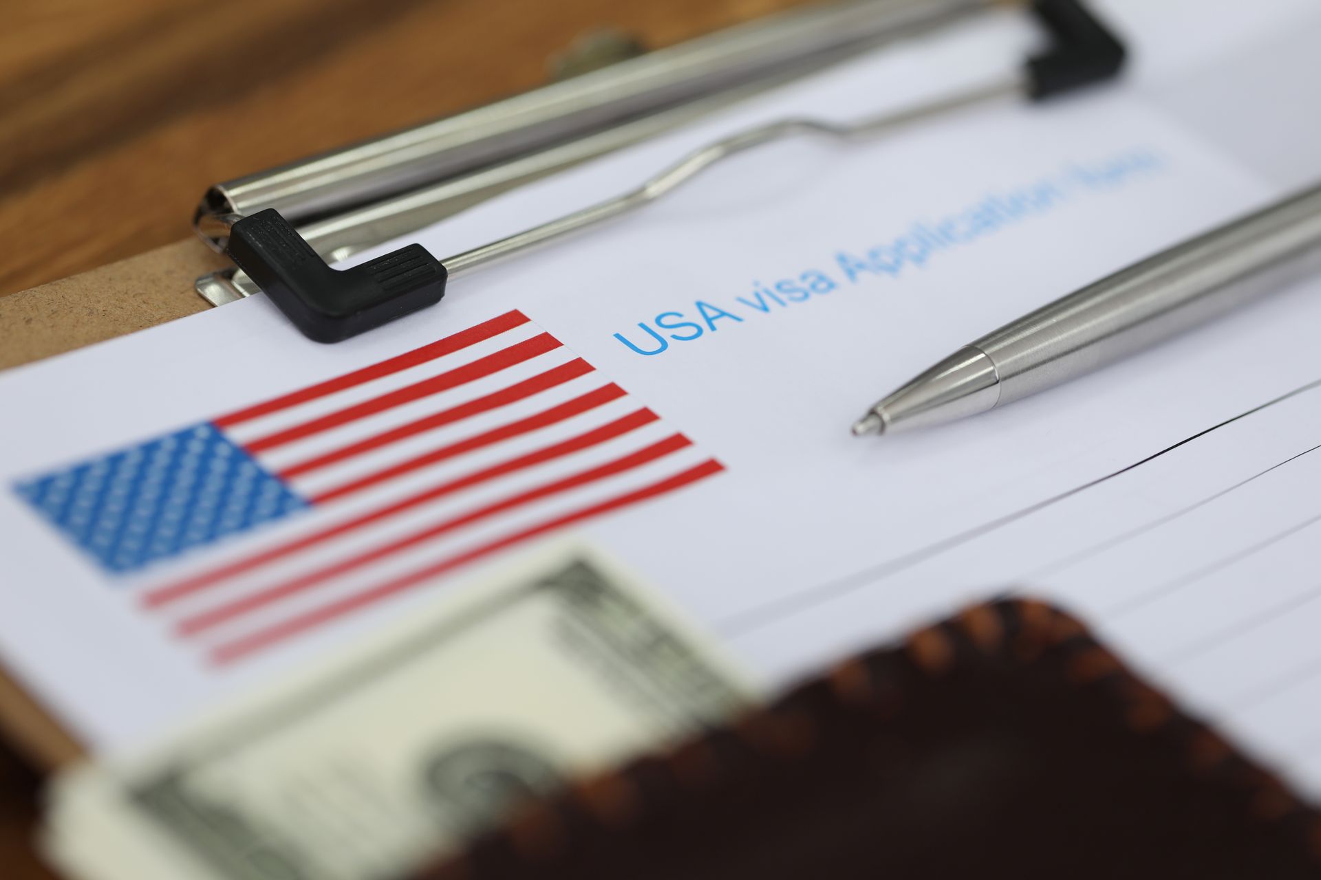 USA visa application form with pen, American flag, and money in wallet.