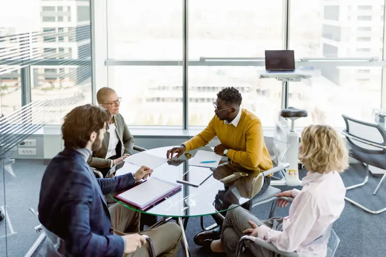 Business team in modern office, gathered at a round table, discussing papers.