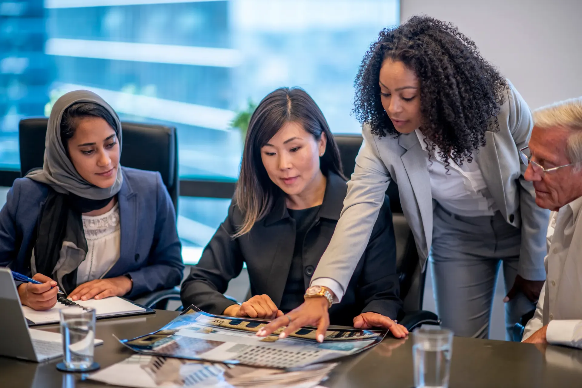A group of people are sitting around a conference table looking at a piece of paper.