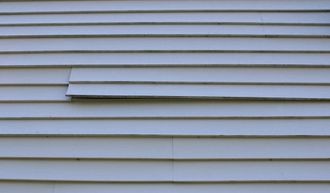 White clapboard siding with a damaged plank.