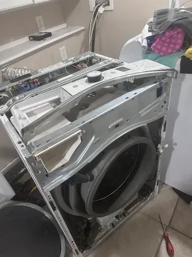 A washing machine with its top and front panels removed, revealing internal components.