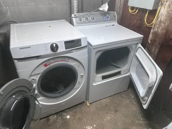 Silver Samsung washer and dryer in a basement. The dryer door is open.