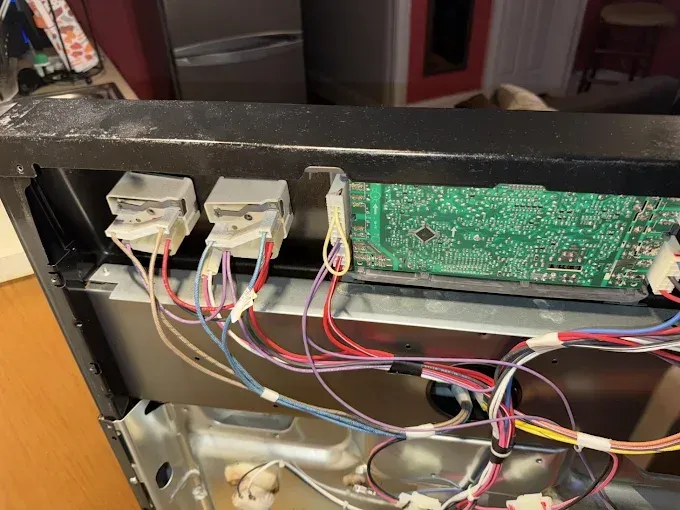 Close-up of the interior of an appliance, revealing wires, connectors, and a circuit board.