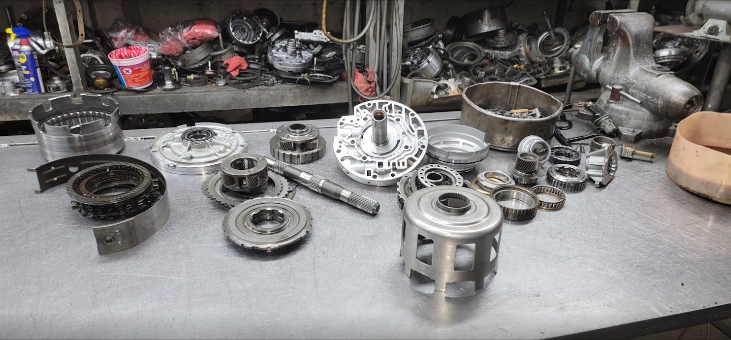 Assorted metal engine parts and bearings arranged on a workbench in a workshop.