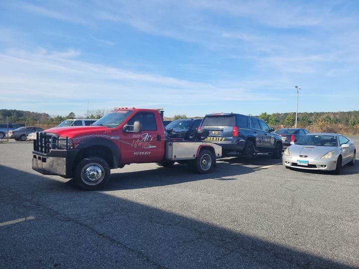 a red tow truck is towing a car in a parking lot .